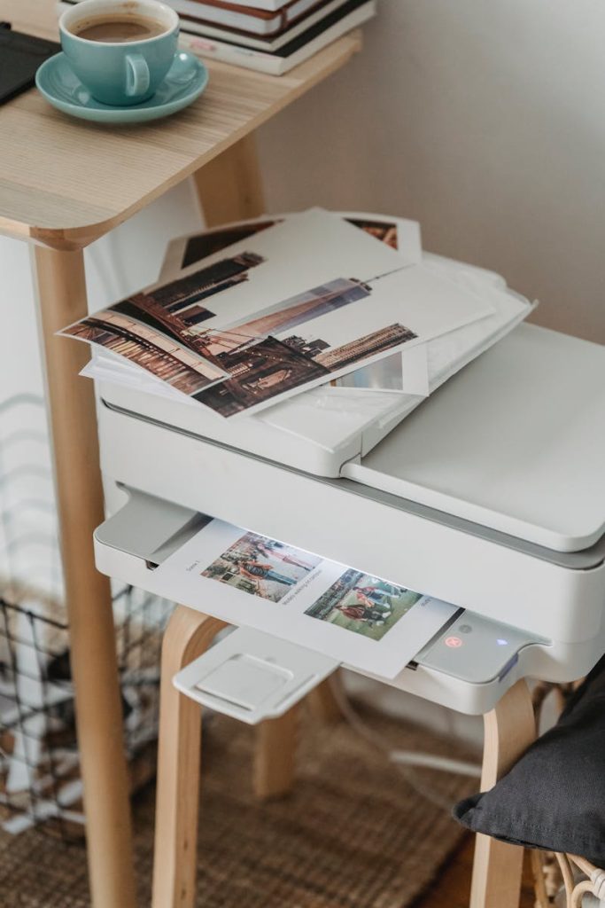 Photos placed on printer near table with cup of coffee